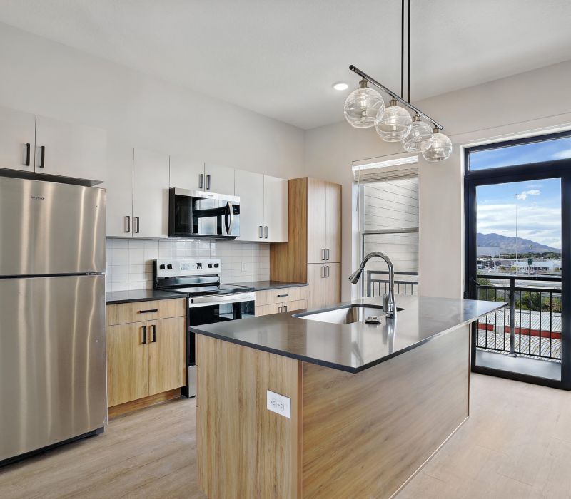 Modern kitchen with wood cabinets, stainless steel appliances, island sink, and large window with mountain view.
