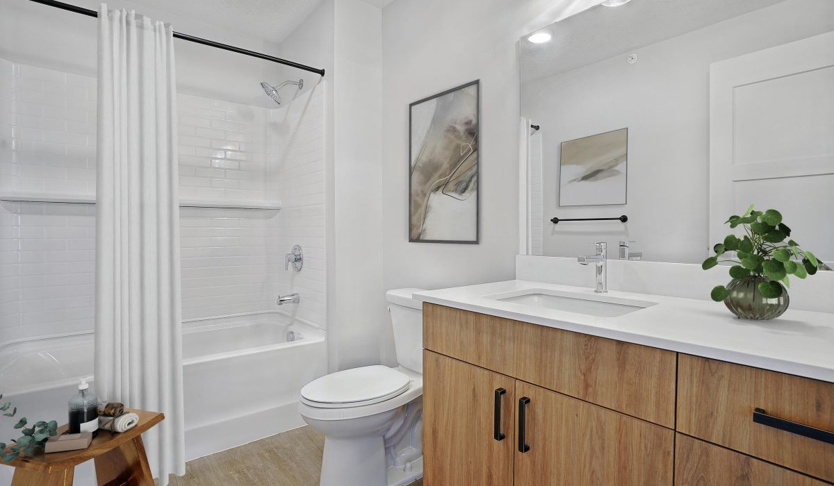 Modern bathroom with wood cabinetry and white tile shower at The Whitney apartments in Salt Lake City, Utah